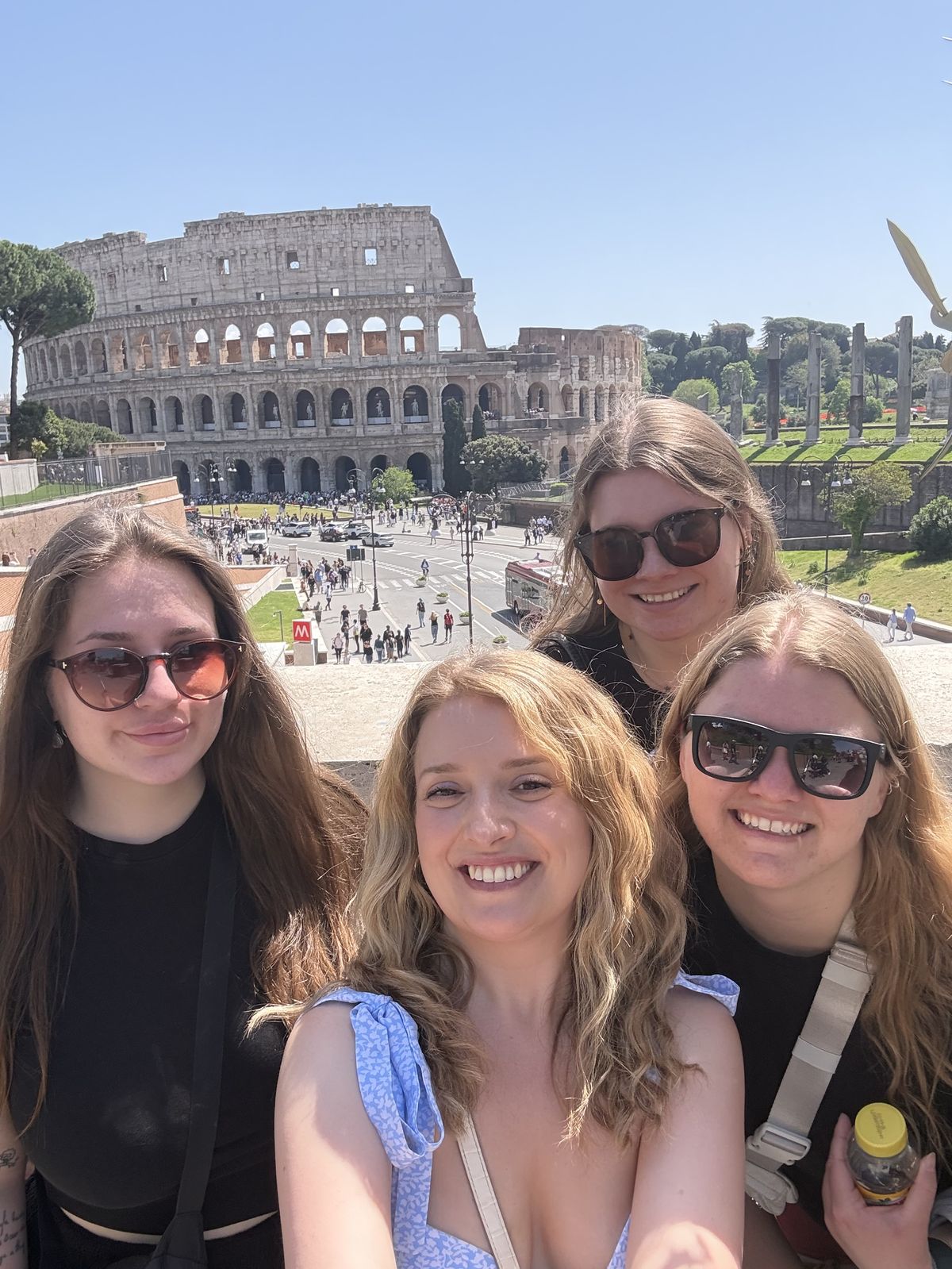 Chloe and three guests smiling together with the Colosseum behind them