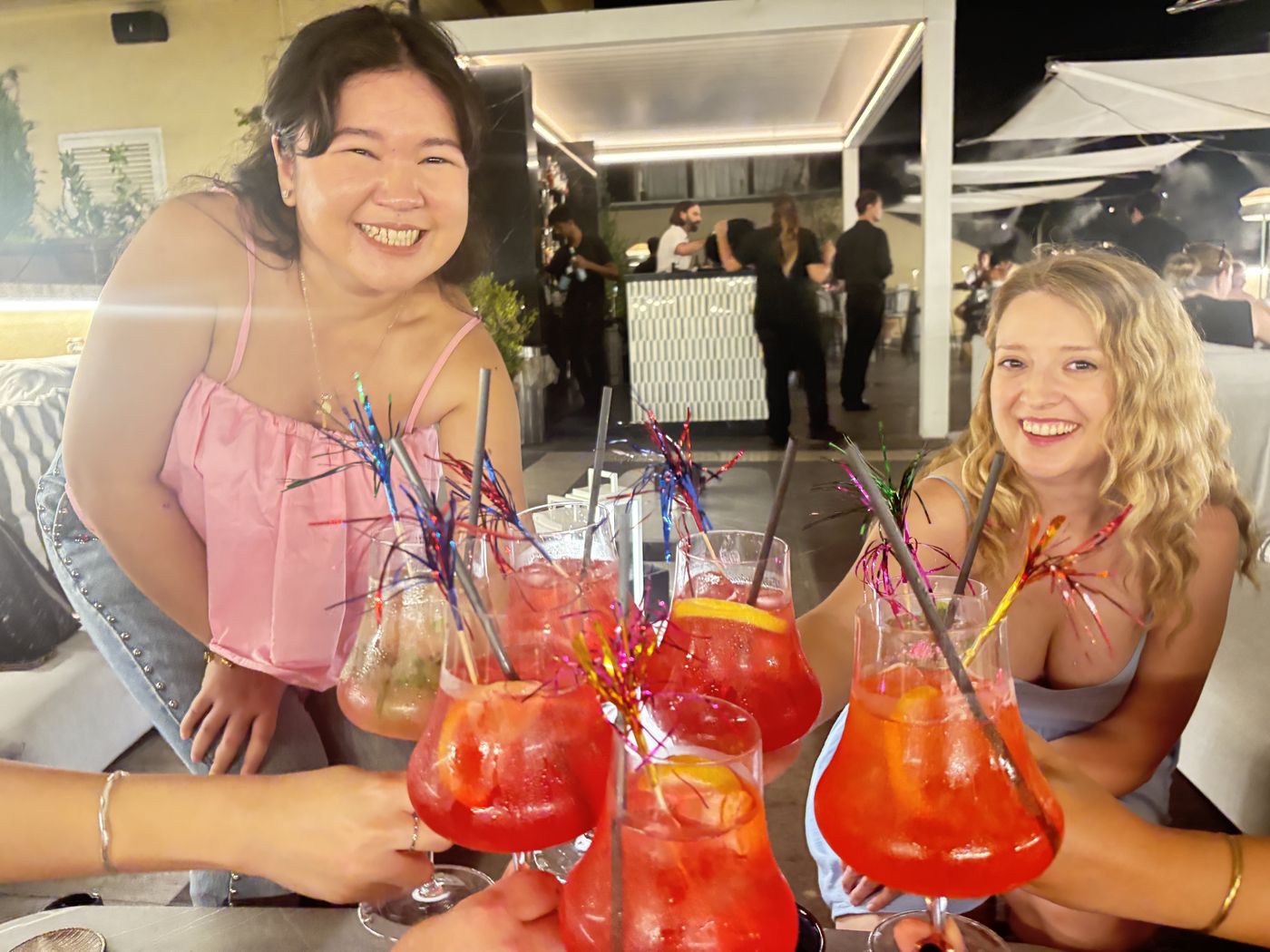 Two Girly Pop guests clinking glitter spritzes at a rooftop bar in Rome